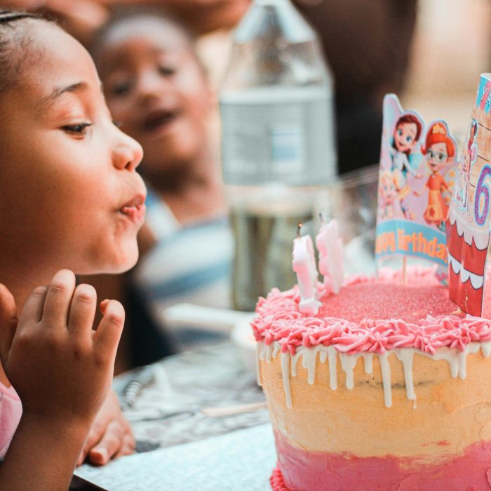 Child blowing out birthday candles on a cake from brewster pastry at a birthday party